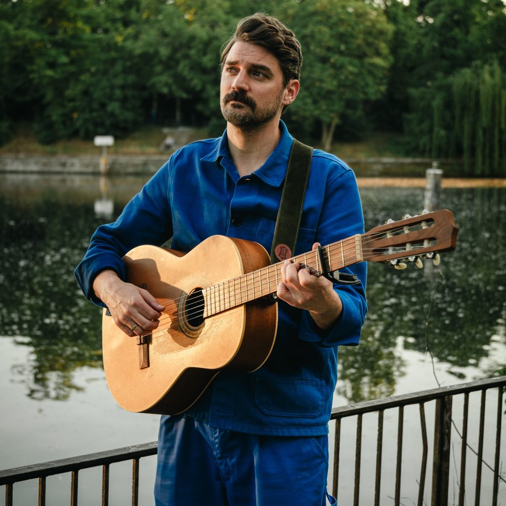 Tim Barker plays the guitar outside for a Concert in Berlin